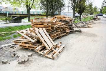 Wooden pallets. Road works in the old town. Stones and pavement tiles on the ground. Reconstruction on the streets. Sidewalk repair. Broken asphalt.