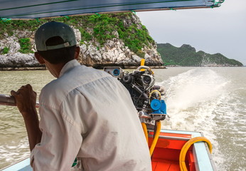 The fisherman is sailing the wooden boat by diesel engine out of the coast for catch the fish and...