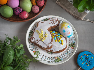 Easter treat on round ceramic plates with colorful eggs and gingerbread on a light background, fresh greens, taken from a close distance