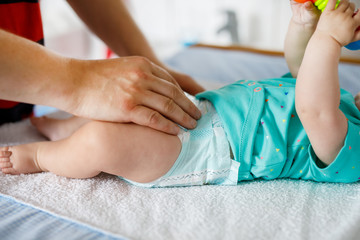 Close-up of father changing diaper of his newborn baby daughter.