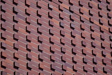 dark red, Burgundy wall with protruding bricks , texture of stone and concrete. structure, background on a Sunny day.