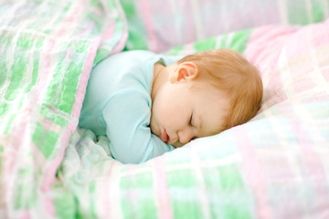 Adorable little baby girl sleeping in bed. Calm peaceful child dreaming during day sleep. Beautiful baby in parents bed. Sleeping together concept.