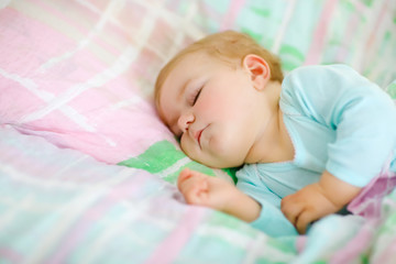 Adorable little baby girl sleeping in bed. Calm peaceful child dreaming during day sleep. Beautiful baby in parents bed. Sleeping together concept.