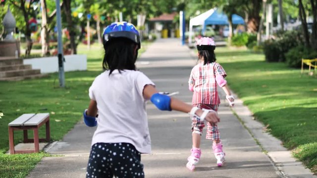 Happy Asian children playing roller skating together in the park outdoor, slow motion.