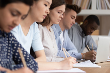 Multicultural students make notes during college lecture