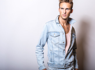 Handsome young man in jeans jacket pose in studio.