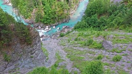 Flight of a quadcopter over a mountain's river canyon. We see the clear, transparent water of the river, it has the emerald color, the trees growing along the coast, and the mountains of northern Mont