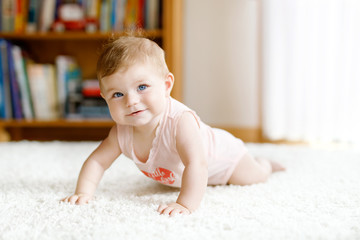 Little funny baby girl lifting body and learning to crawl.