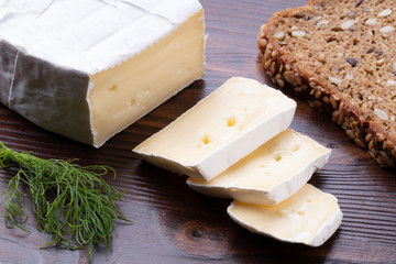 Sliced smelly camembert cheese with bread on a wooden rustic table