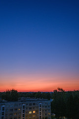 red sunset over city with housing and internet provider cables in the sky