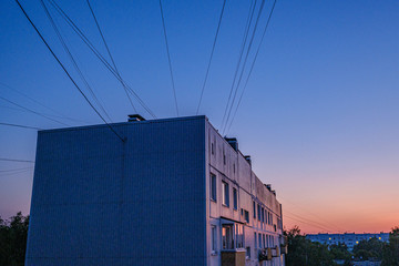 red sunset over city with housing and internet provider cables in the sky