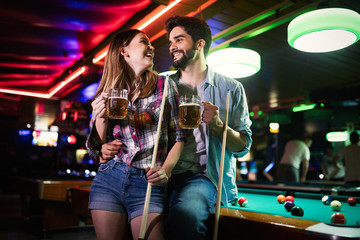 Happy young man playing snooker with his girlfriend. Happy loving couple.