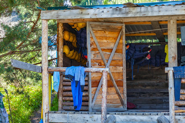 Fototapeta na wymiar A wooden house, a hut in the forest near a mountain river with clothes, helmets and rafting equipment, t-shirts and pants for drying on the railing and windows. Extreme Sports and Recreation