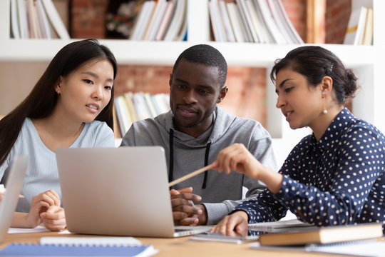 Multiethnic Students Discuss Project Studying At Laptop Together