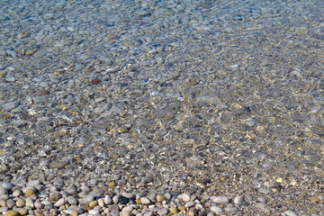 Sea wave moves to a pebble beach. Summer sunny day. View from above