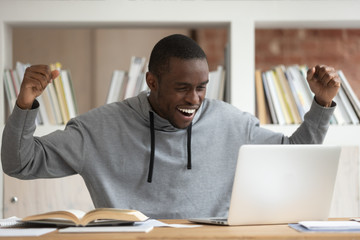 Happy black male student get pleasant email on laptop