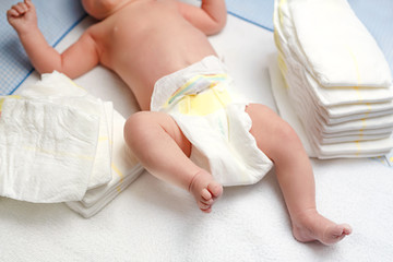 Fototapeta na wymiar Feet of newborn baby on changing table with diapers. Cute little girl or boy two weeks old. Dry and healthy body and skin concept. Baby nursery.