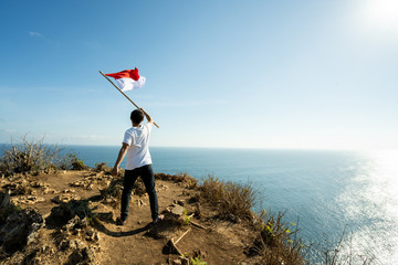 asian man with indonesian flag of indonesia on top of the mountain