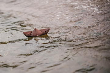 Fototapeta na wymiar brown paper boat floats on water