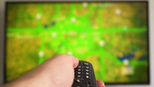 Fast switching the television news channels. Hand switches the channels by remote control Flat screen TV. Online video streaming service