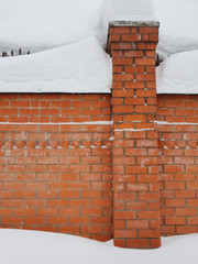 brick fence covered with a large layer of snow in winter