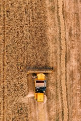 Aerial view of the combine harvester agriculture machine working on ripe wheat field.