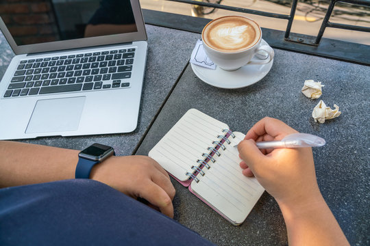 Human hand writing notebook at coffee table