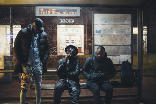 three young african men waiting on the bus stop