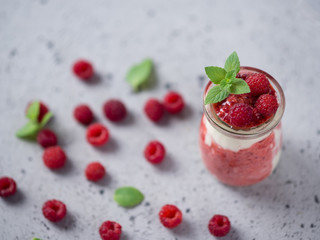 Raspberry parfait dessert Breakfast in glass jar on grey table