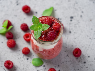 Raspberry parfait dessert Breakfast in glass jar on grey table