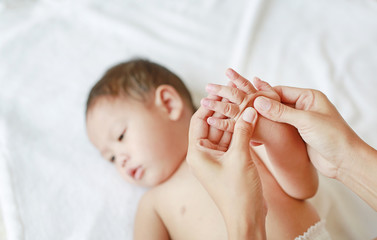 Mother hands massaging finger of baby on the bed at home.