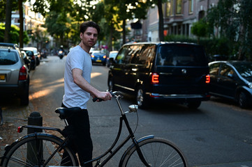 Obraz premium Healthy and spontaneous young man crossing the street while walking next to his bicycle 