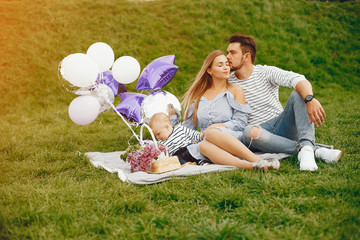 A young and beautiful blonde mother in a blue dress, along with her handsome man dressed in a white...