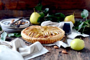 Pears tart with frangipani on a dark wooden table