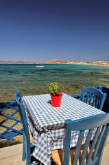 Typical blue Greek table and chairs at a taverna and beach, Agios Prokopios Beach, Naxos, Greek Islands - obrazy, fototapety, plakaty