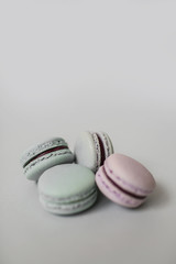 Top view of a pile of sweet macaroon biscuits of pastel color lying on light grey background. Copy space.