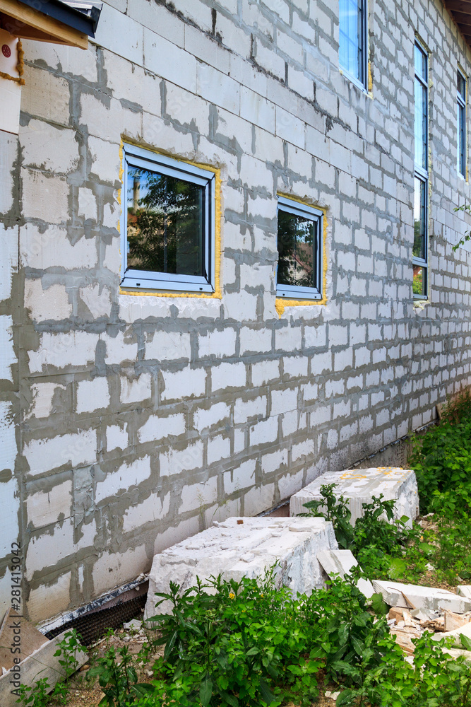 Poster facade of cottage under construction with new inserted windows. blocks of foam concrete blocks sawn 