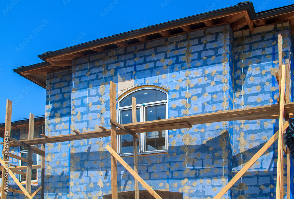 Poster facade of cottage under construction with building grid applied to walls and guides for plaster appl