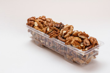 Walnuts in a plastic container on the white background.