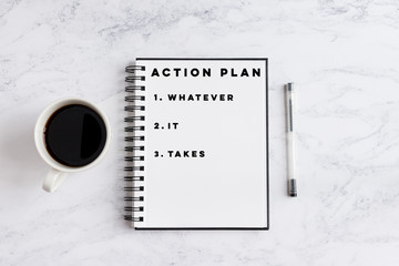 Action Plan Whatever It Takes writing on notebook. Notebook on desk with coffee cup and a pen.
