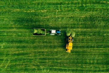 Aerial view of harvest field with tractor moving hay bale