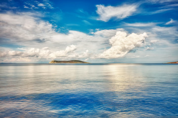 Beautiful landscape of an island, calm blue sea and clouds.