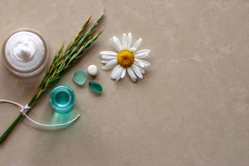 Flat view. Cream, chamomile, green spikelets and pebbles. Selective focus. Brown background blurred. Place for text.