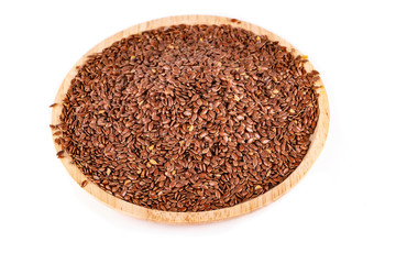 The flax seeds in a wooden plate isolated on a white background