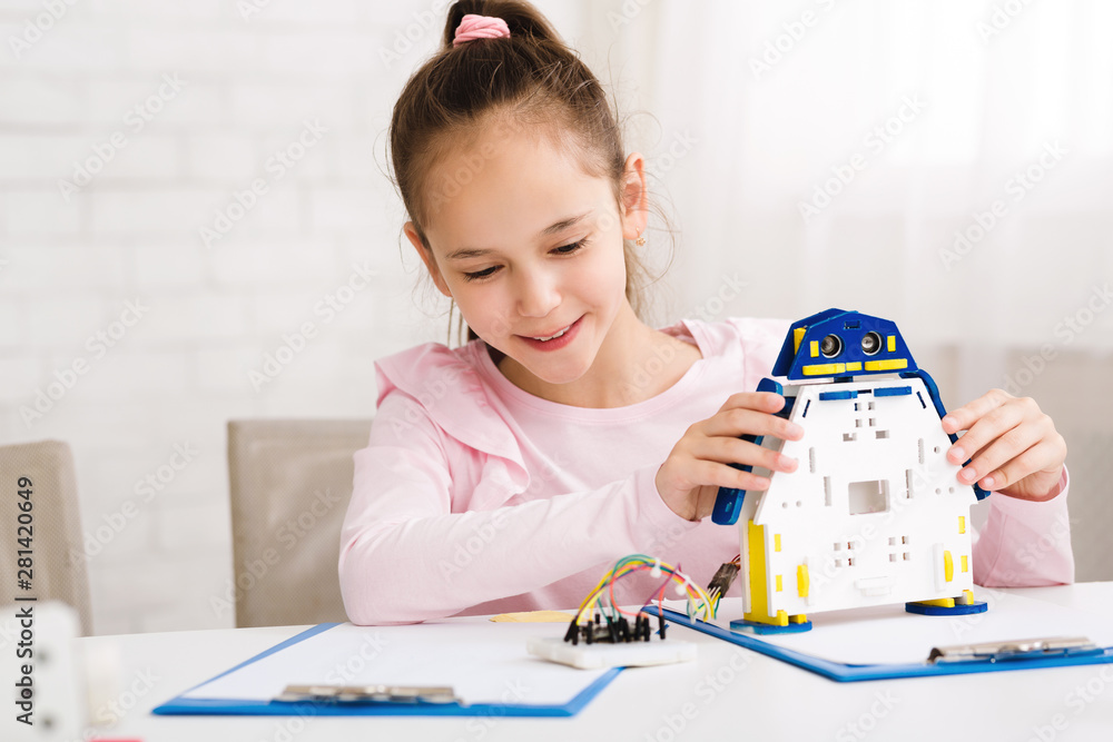 Poster Cheerful smart schoolgirl constructing robotic device at lesson