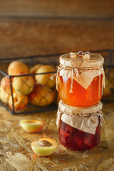 Apricot jam on a wooden rustic background. Two jars of fruit homemade marmalade. Glass jars with different kinds of fruits.