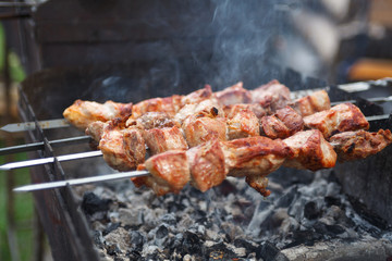 Close up selective focus fresh hot delicious bbq kebab grilling on open grill, food festival, outdoor kitchen, roasting on skewers, summer picnic, food-court