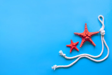 Obraz na płótnie Canvas Two red starfishes and white nautical rope.Flat