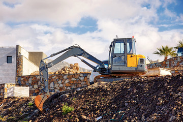 Earth mover excavator parked over the hill at a real estate building construction site