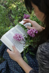 Girl with a Bible in her hands and lilac flowers.